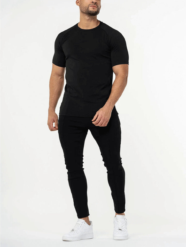 Man wearing a black t-shirt and black pants with white sneakers on a white background